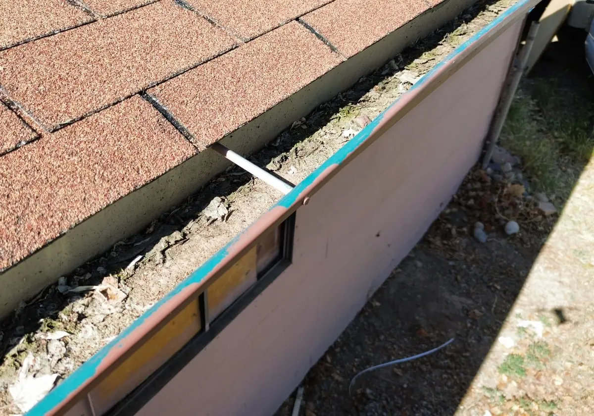 Granules and debris collected along the gutter line before the replacement