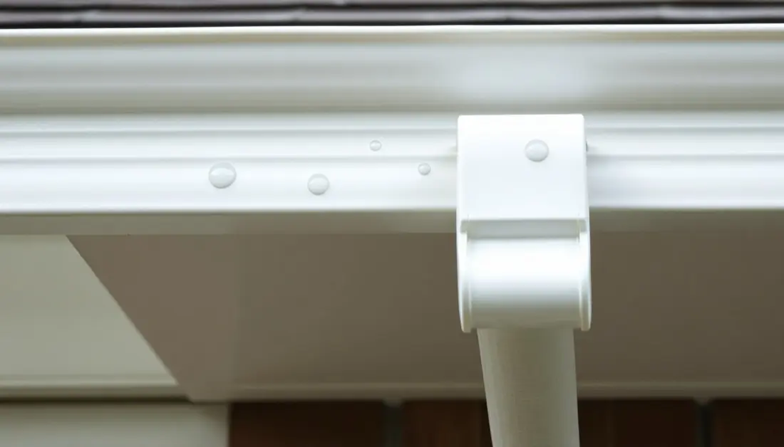 Soft round hail dents in a white aluminum gutter